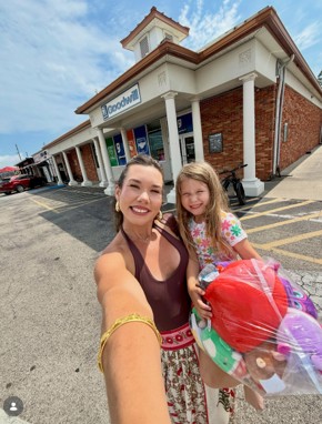 A women and her daughter standing in front of a store