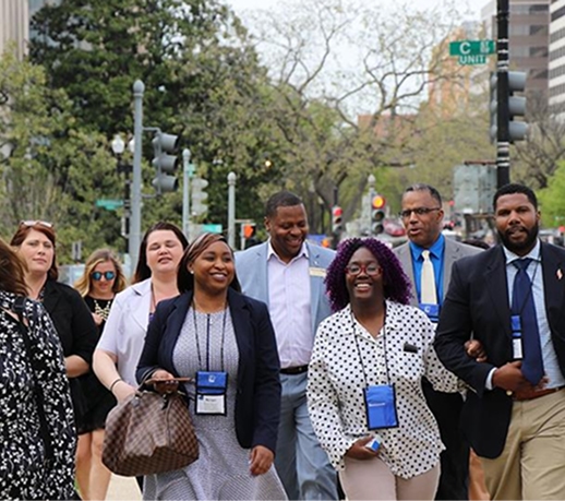Diverse group of professionals walking together on a city sidewalk, wearing badges.