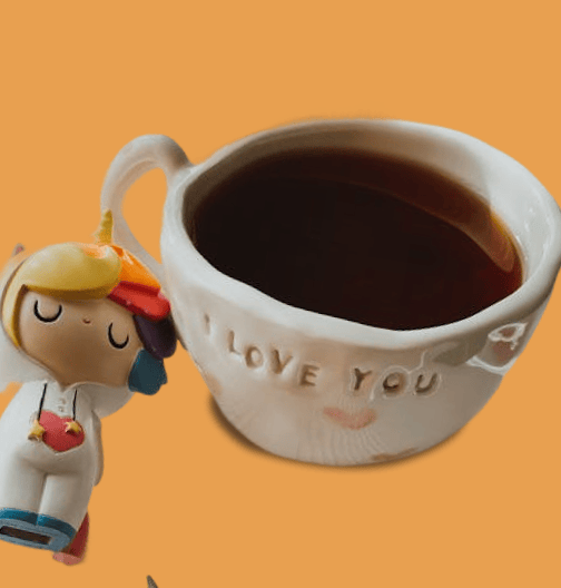 Toy figurine leaning against a white mug embossed with 'LOVE YOU', filled with dark coffee, on an orange background.