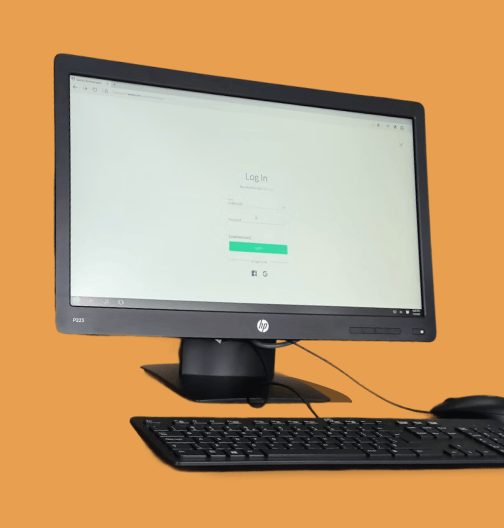 HP desktop monitor with keyboard and mouse on orange background displaying a login screen.